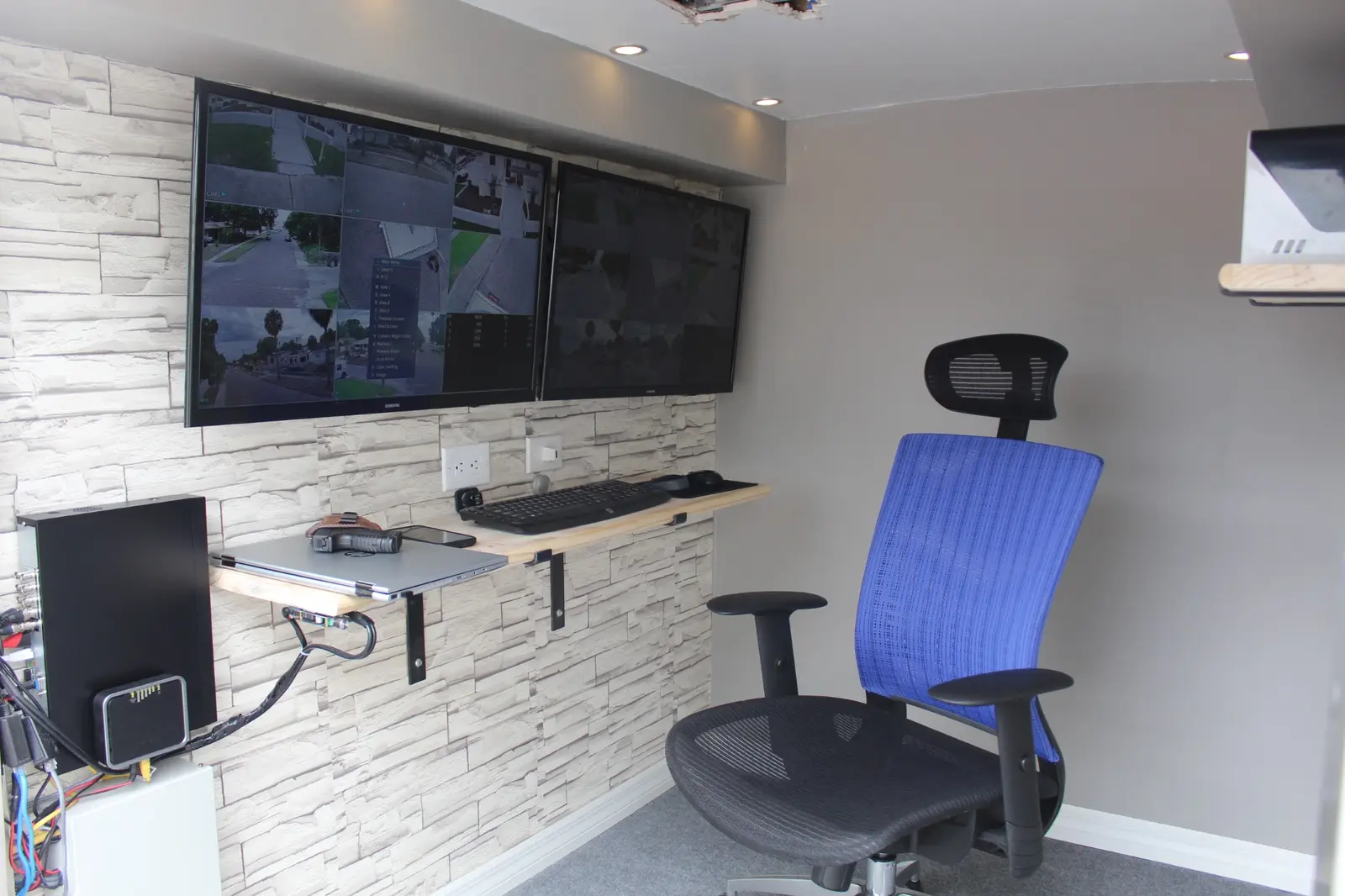 Finished Mobile GuardShack interior with two surveillance displays, laptop shelf, keyboard, network equipment and operator chair